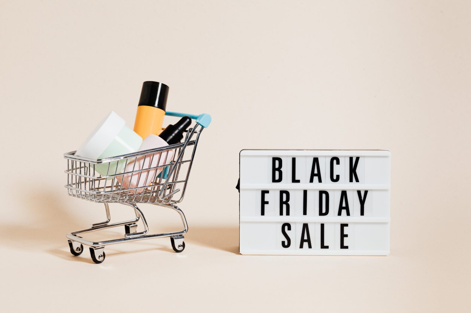 skin-care-products-in-a-shopping-cart-beside-a-black-friday-sale-signage-on-beige-background