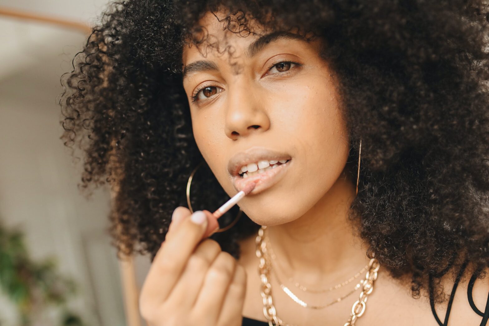 Black-woman-in-gold-necklace-putting-on-lipstick