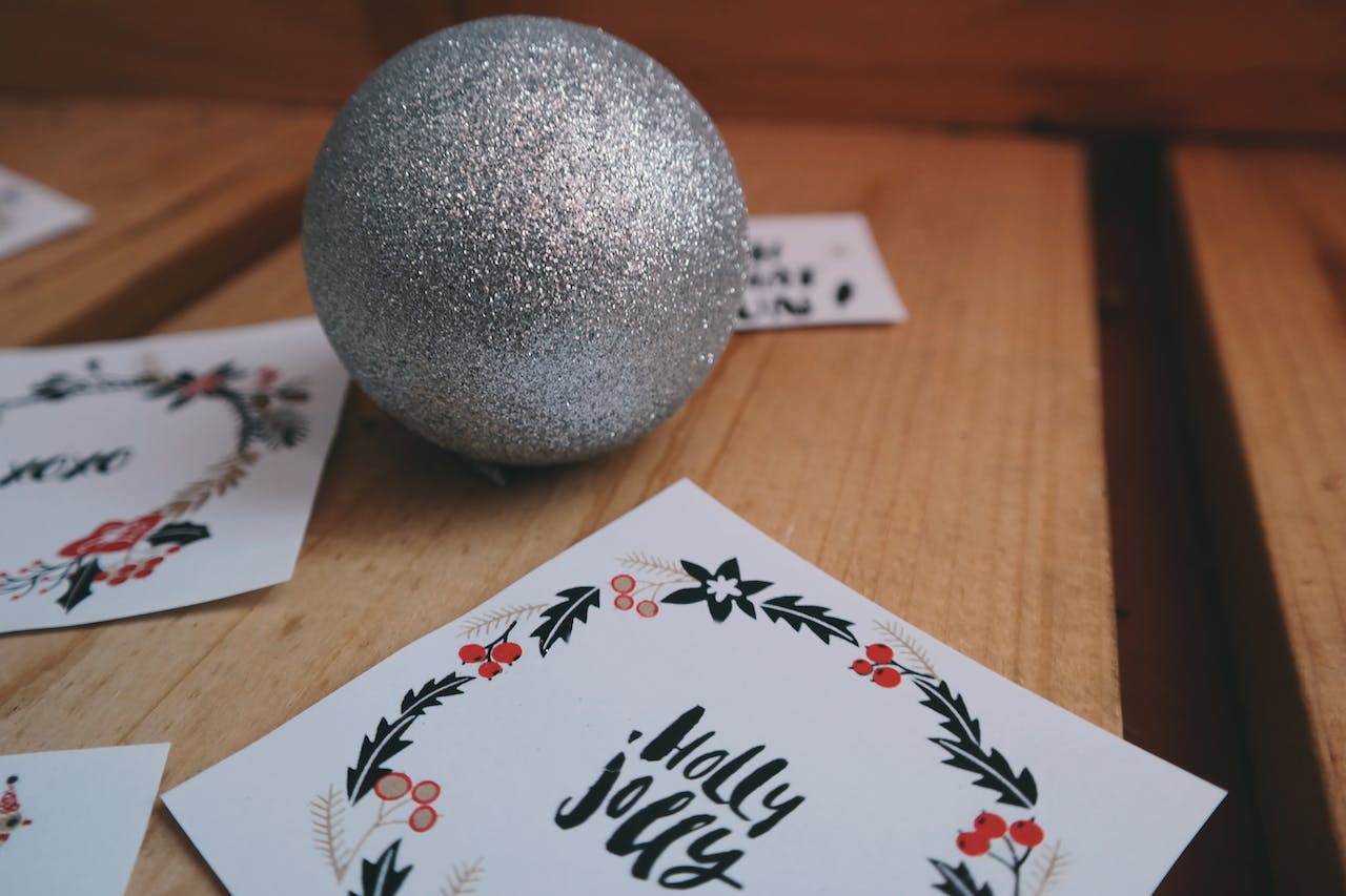 Here is what to write in a Christmas card. Pictured: a card that says holly jolly next to an ornament.