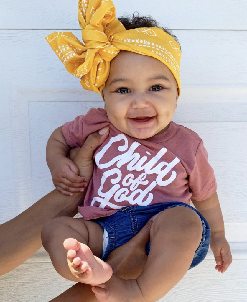 a baby with a head wrap being held up by a person's arms