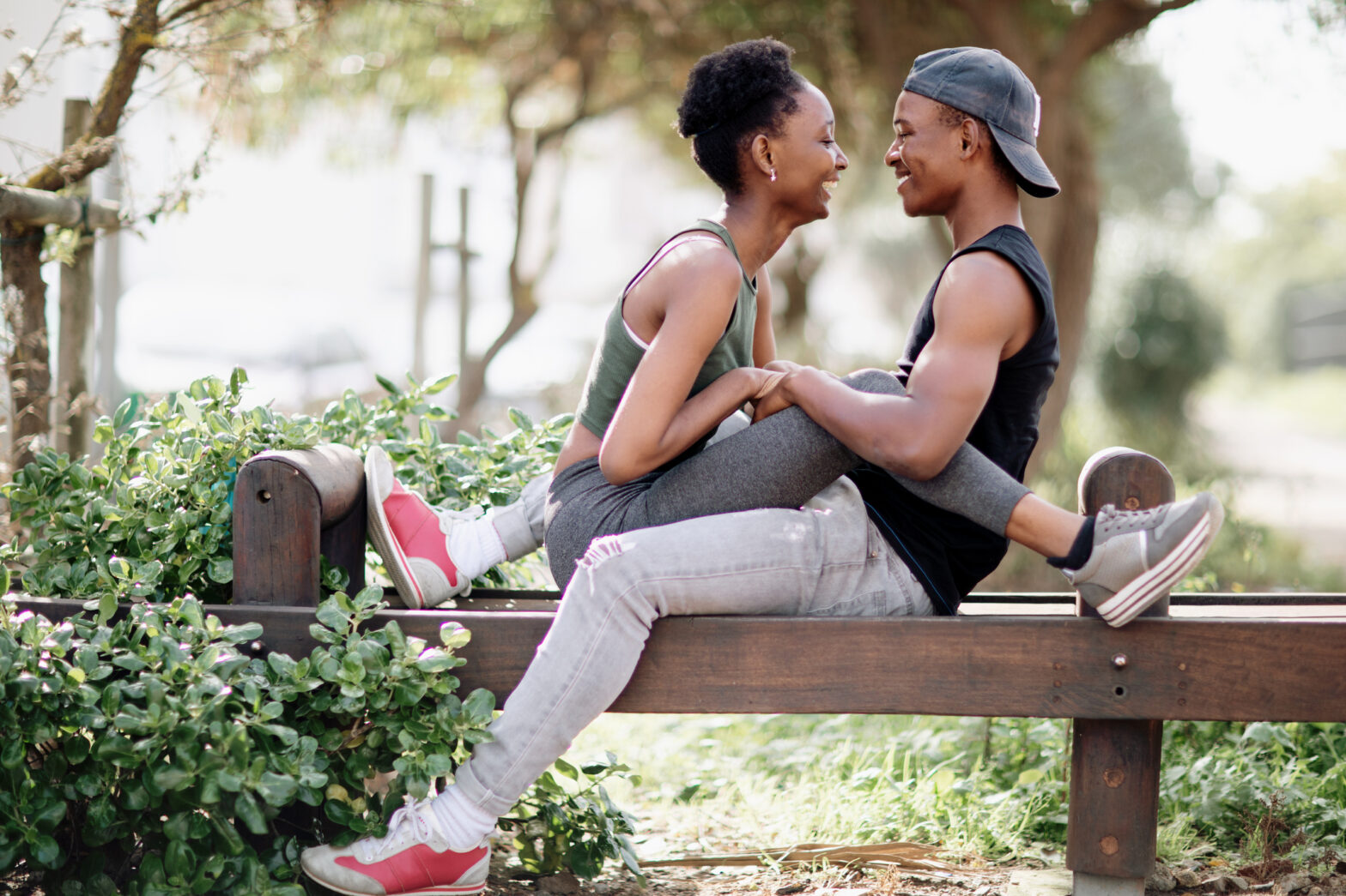 Beautiful laughing loving couple sitting over each other on a bench