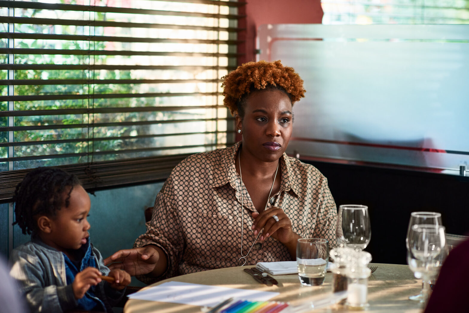 Black woman in restaurant with son at table