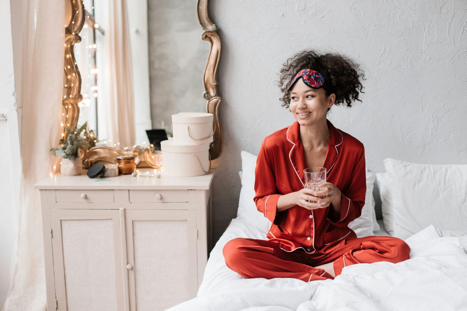 woman-wearing-red-pajamas-sitting-on-bed-holding-a-glass-of-water