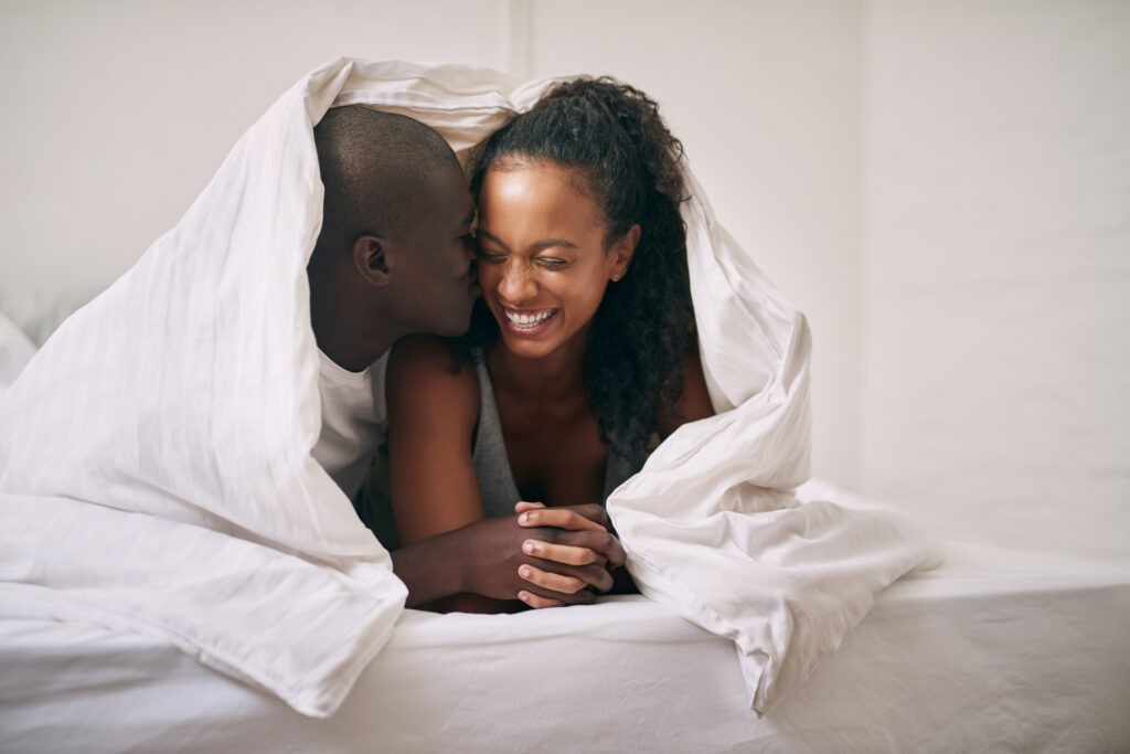 Cropped shot of an affectionate young man kissing his wife on the cheek under the covers in their bedroom at home