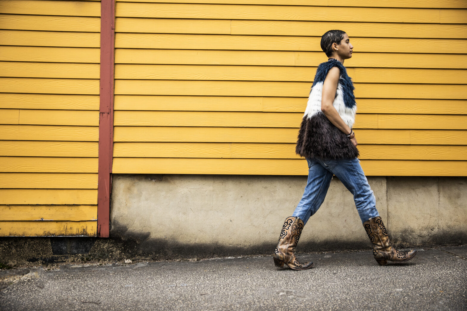 Fashionable young woman walking in front of yellow urban home