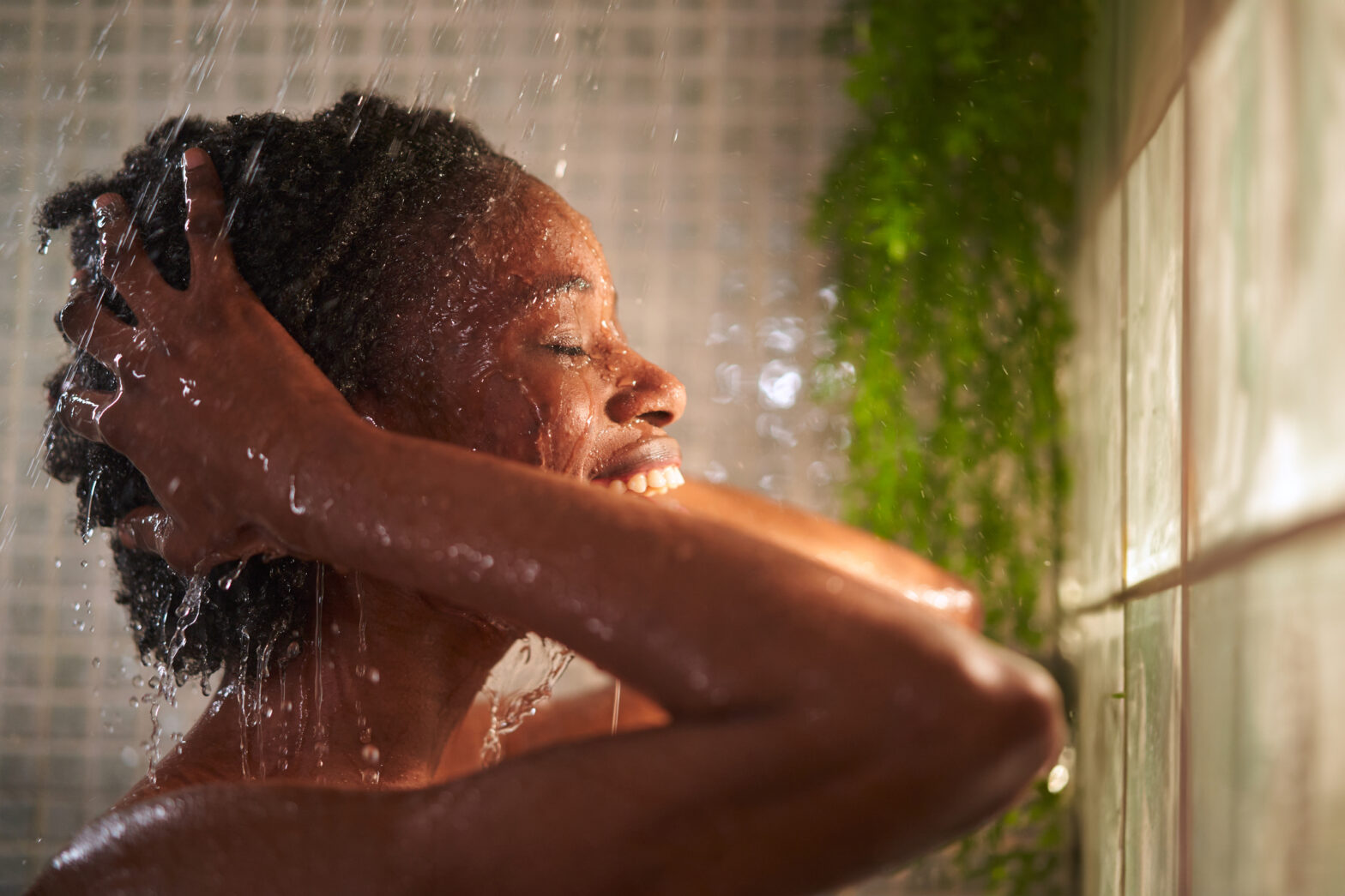 Close up image of a woman washing her hair cheerfully, smiling and enjoying the shower.
