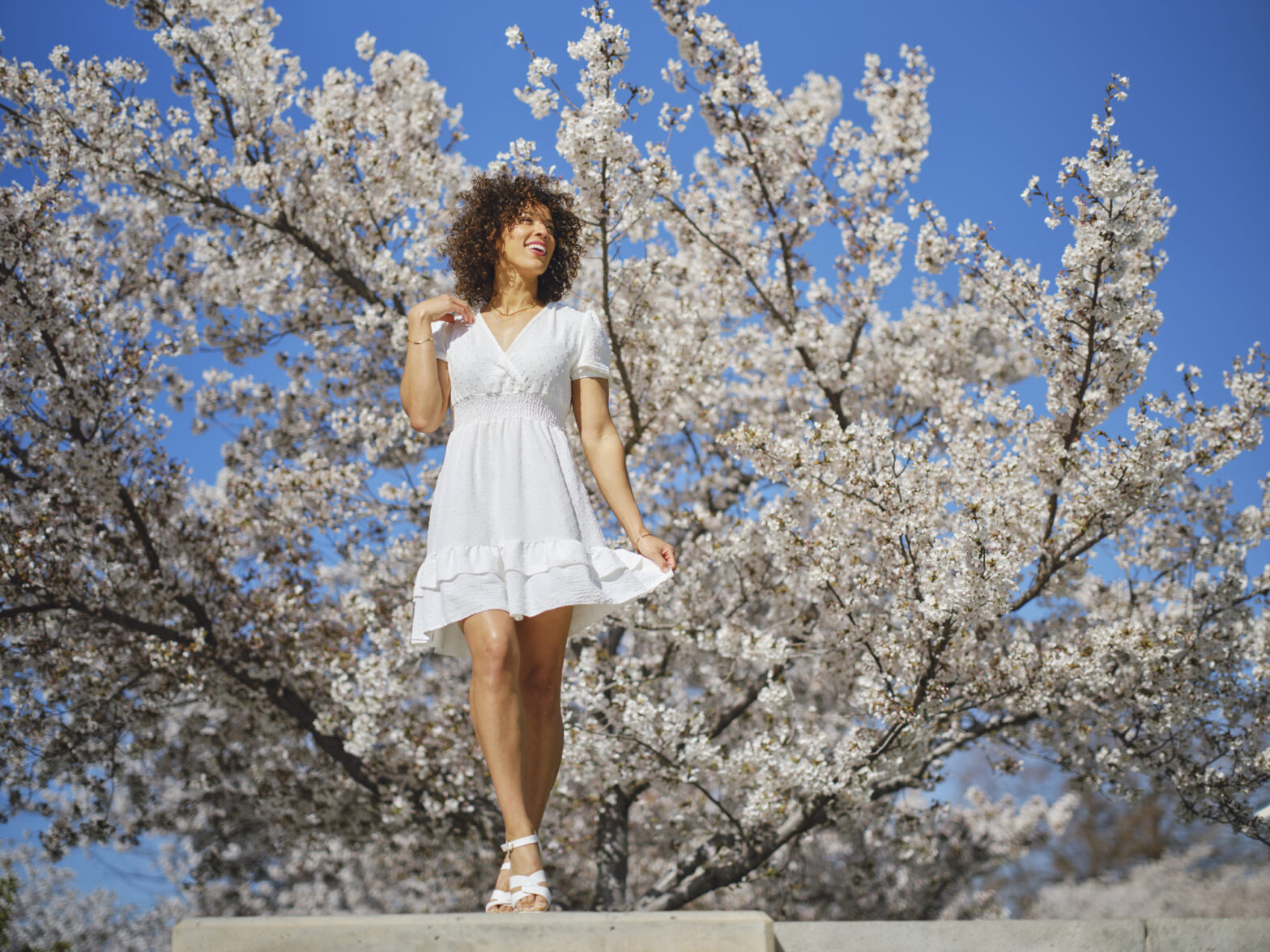 A portrait of a multiracial woman in springtime outdoors among cherry blossoms.