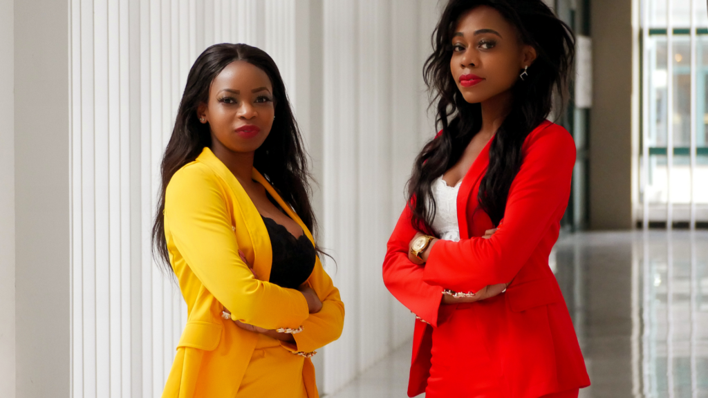 Young Black Women dressed in a yellow suit and a red suit with shape-fitting blouses underneath