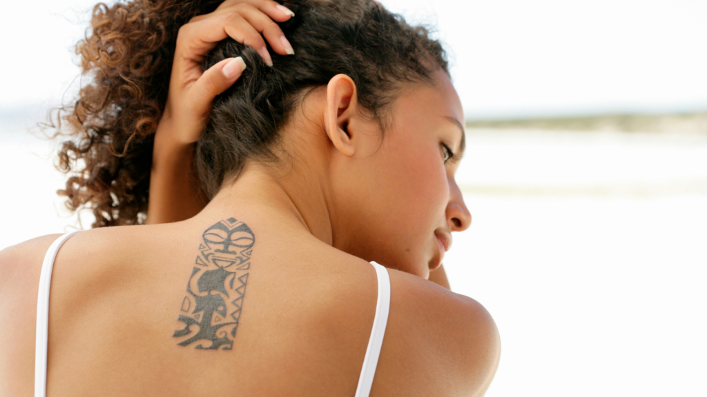 Family crest tattoo on spine of woman holding her hair up