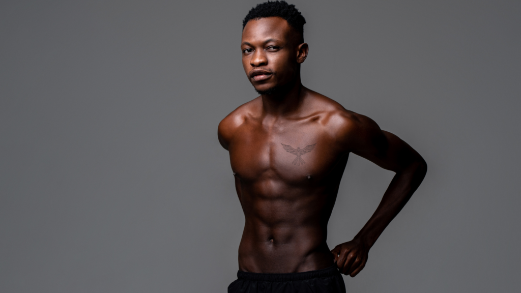 Male model with shirt off in front of grey background, eagle symbol tattoo on chest