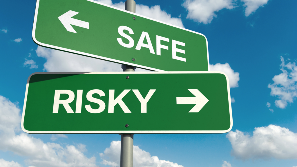 Street signs intersecting safe and risky with arrows with sky and clouds in background