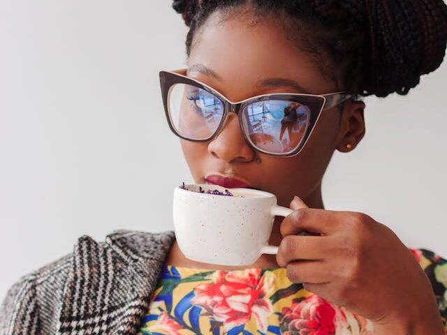 Black woman in colorful dress sips tea