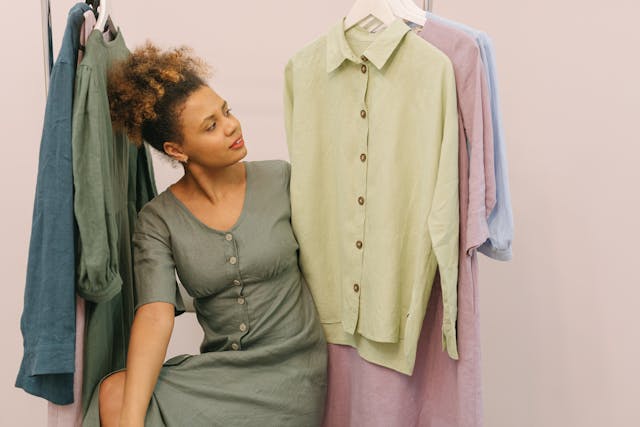 African-American woman with puffy ponytail looks at three shirts to buy