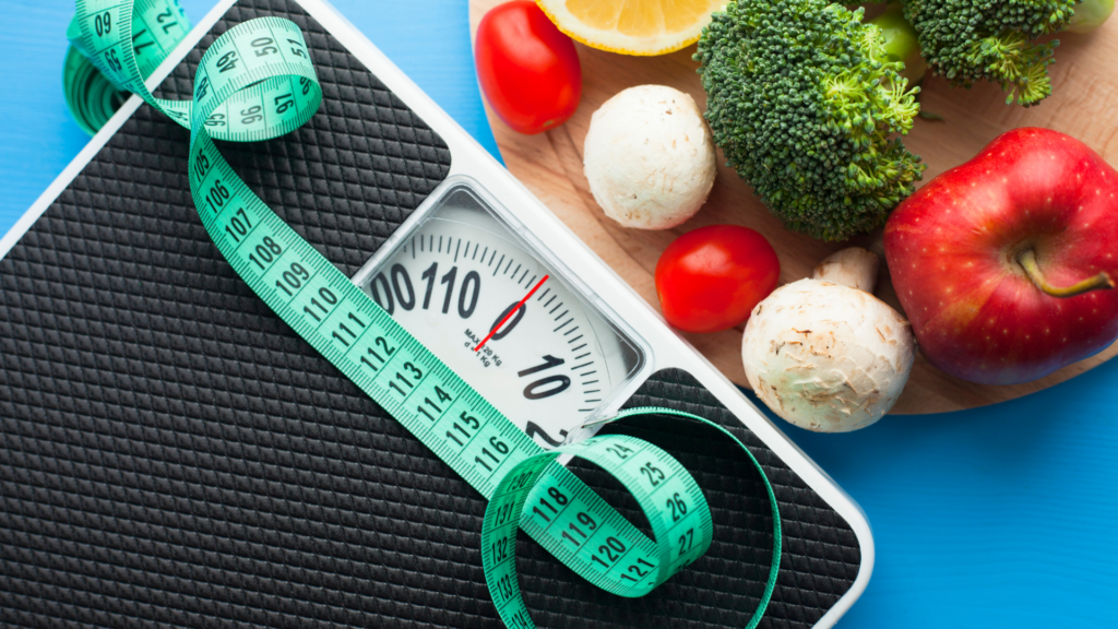 Scale with measuring tape and raw vegetables on a blue background