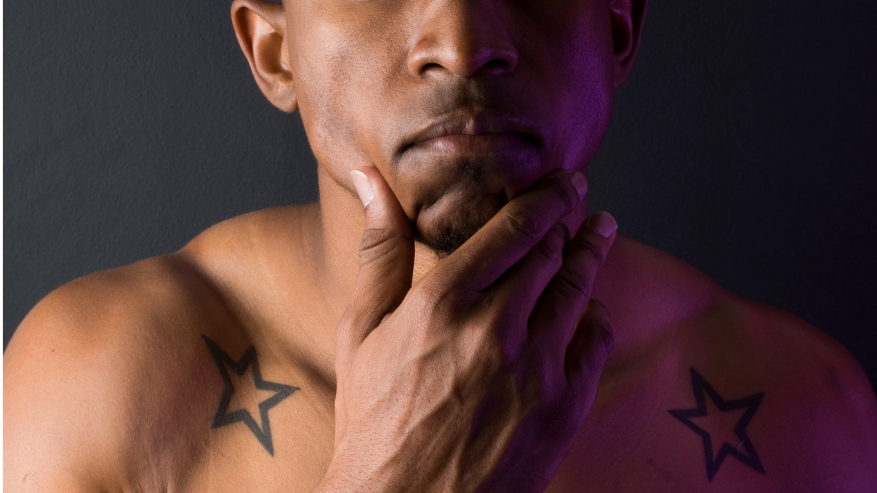 Shirtless man with hand on his chin and two bold star graphic tattoos on each shoulder