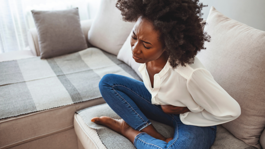 Young woman lying on her sofa suffering from period cramps at home