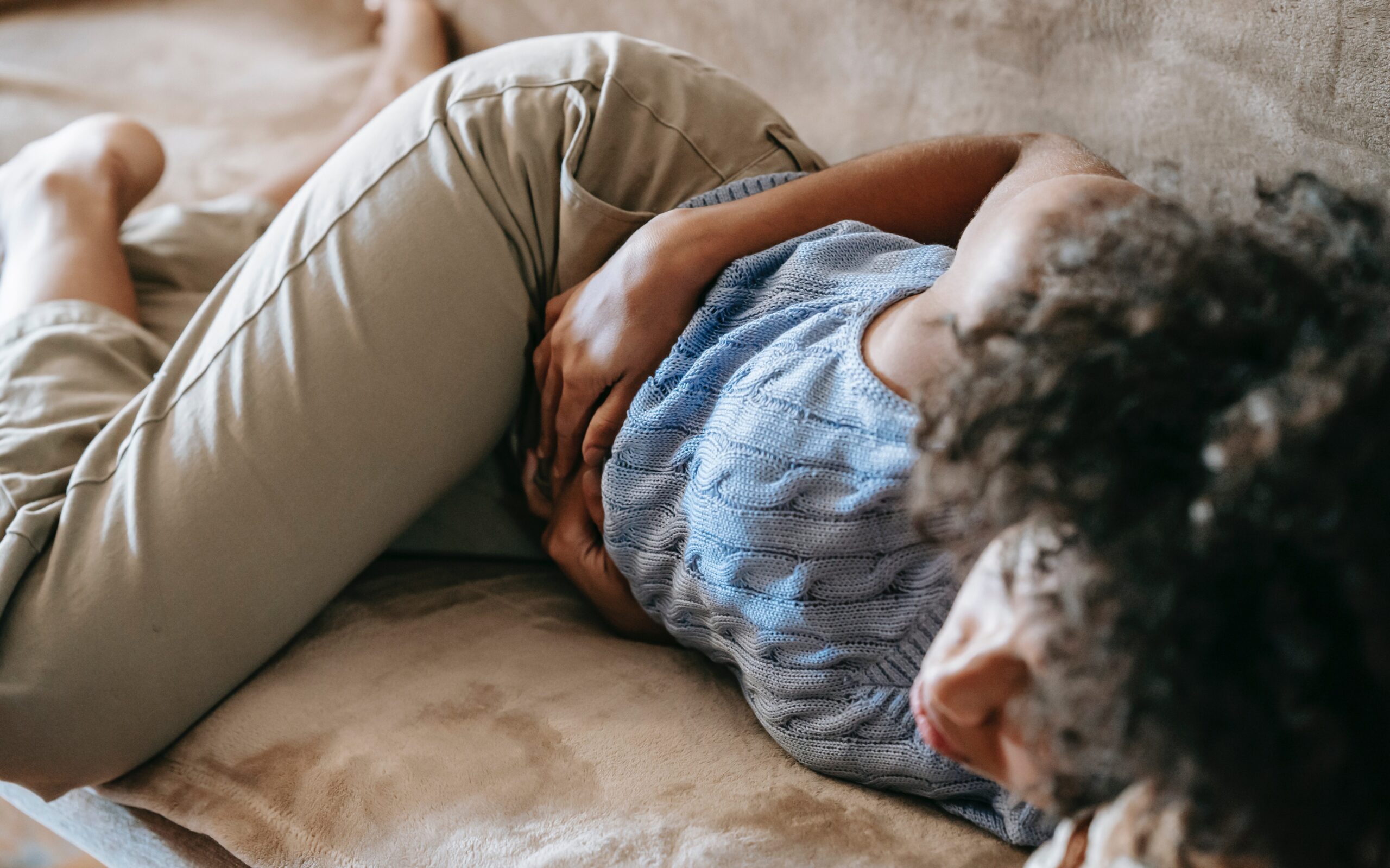 Can you ovulate without a period? Pictured: a woman holding her abdomen.