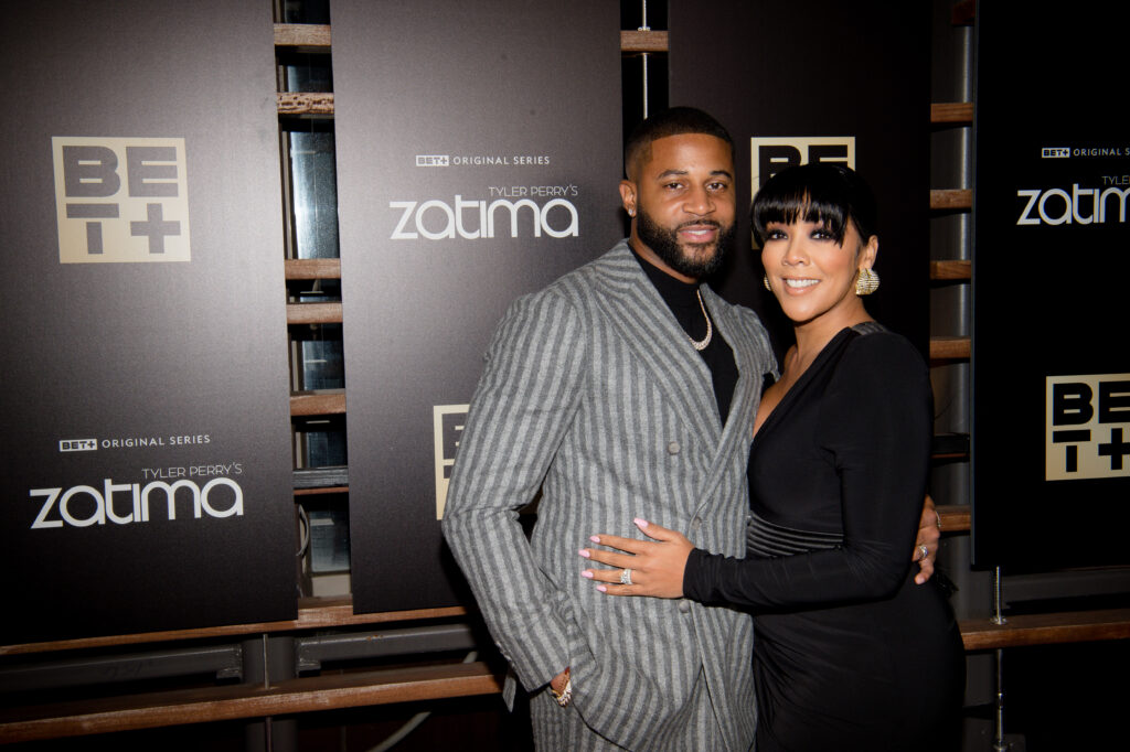 Actors and parents Devale and Khadeen Ellis hugging and posing at a show premiere, wearing grey and black