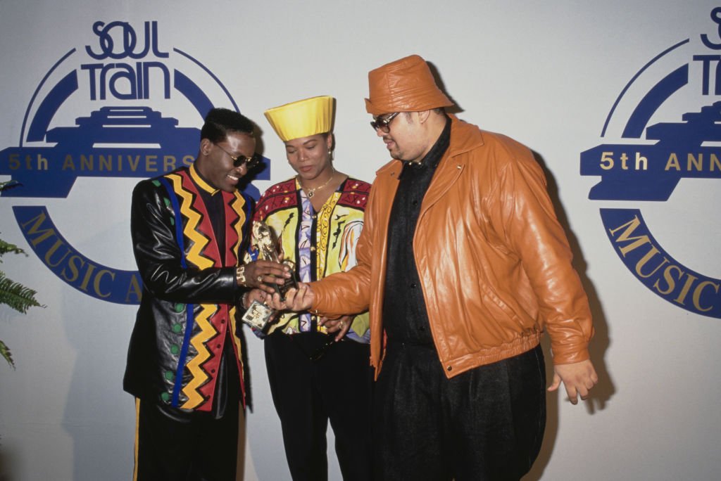 American singer-songwriter and actor Johnny Gill, American rapper and actress Queen Latifah (Dana Elaine Owens), wearing a yellow hat and sunglasses, and Jamaican-born American rapper Heavy D (Dwight Arrington Myers, 1967-2011), wearing a tan leather jacket and a matching hat with sunglasses, attend the 1991 Soul Train Music Awards, held at the Shrine Auditorium in Los Angeles, California, 12th March 1991.  