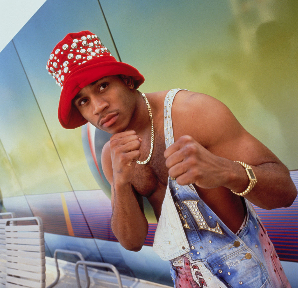 Barechested LL Cool J in fighting position while wearing a one-hooked pair of overalls