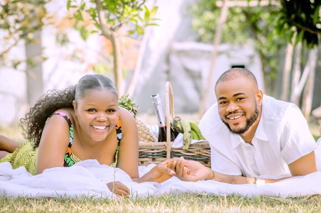 Couple holding hands and laying down for a picnic with wine 