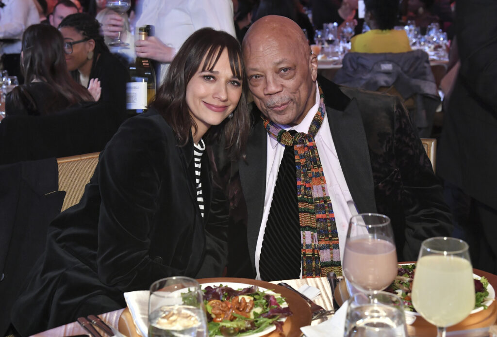 Rashida Jones and Quincy Jones sitting at a table together.